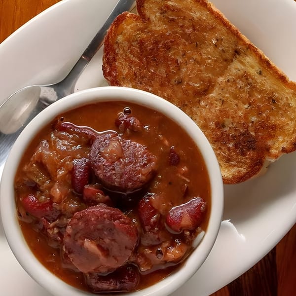 A bowl of Boudreaux's II red beans and rice with sausage, served with toasted bread.