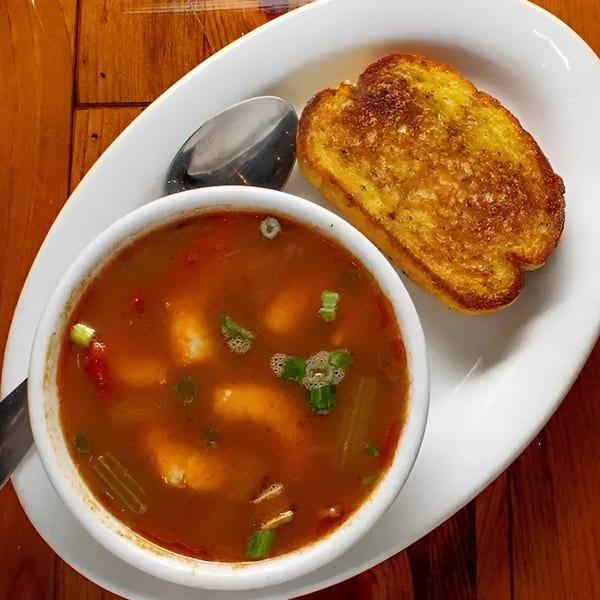 A bowl of Boudreaux's II Cajun gumbo with shrimp and vegetables, served with toasted bread.
