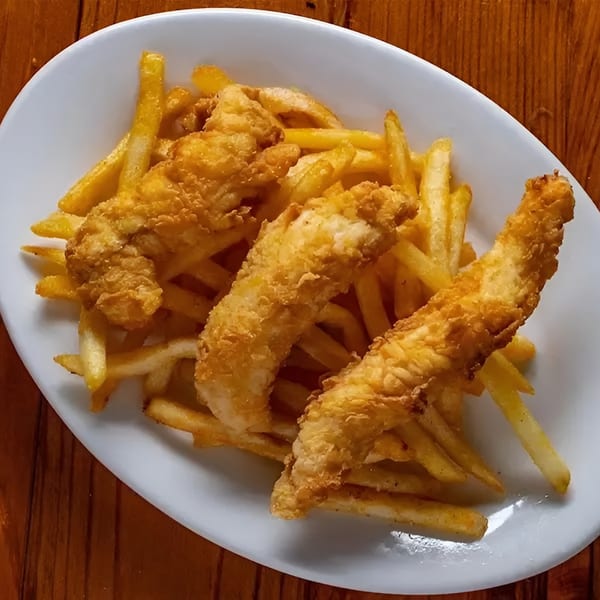 Crispy fried chicken tenders and golden french fries on a white oval plate.